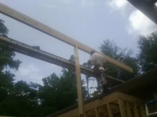 Carpenter setting a ridge beam over a new addition frame — Ice Dam Removal by Roofing Brothers in Stonewall