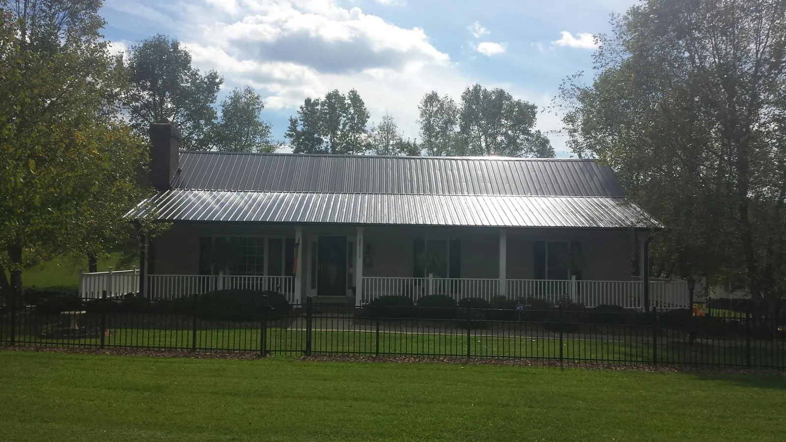 Gray metal roof on a brick ranch with a full width front porch — Gutter Guard Installation work by our crew in Stonewall